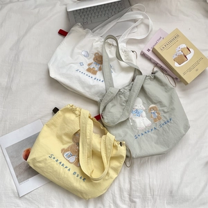 Detailed embroidery on canvas tote bags in white, yellow, and mint green colors