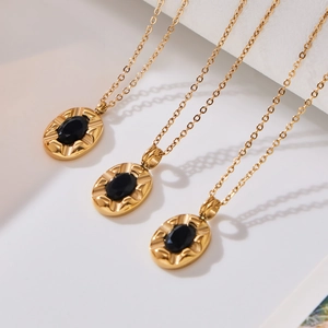 French vintage gold necklace featuring oval black zircon pendants on a white podium