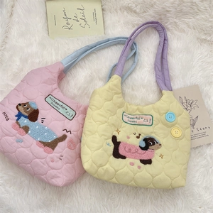 Detalle de bolso acolchado con bordado de perro y botones de asa en contraste
