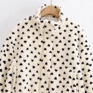 Gemütliche Fleecejacke für Damen in Creme mit schwarzem Herzmuster am Kleiderbügel