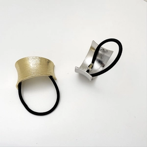 Detailed close-up of gold and silver U-shaped brushed metal rings on black hair ties