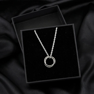 Silver tone interlocking triple ring pendant necklace in a black gift box on silk
