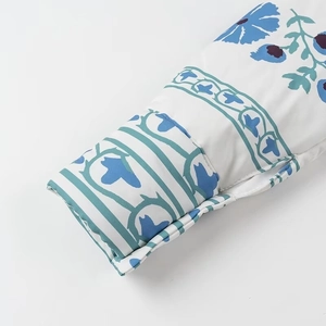 Détail de l'imprimé floral et du bord matelassé sur le manteau d'hiver en coton bleu
