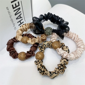 Set of five scrunchies featuring rhinestone balls in black, gold, and leopard print