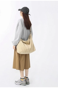 Detail view of large beige corduroy tote bag worn over the shoulder on a model's back