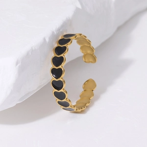 Detailed view of gold plated heart ring with black enamel inlay on marble stone base