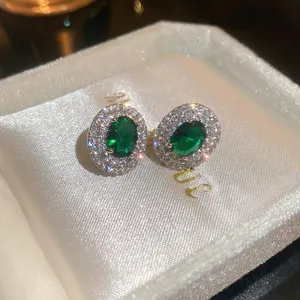 Elegant silver stud earrings featuring oval green emerald and double halo zircon pavé