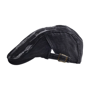 Detail of distressed black denim beret with frayed holes and brass adjustable buckle