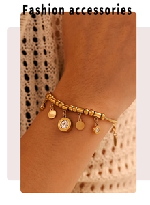 Detail of gold bead bracelet with zircon pendants and round tags on a female wrist