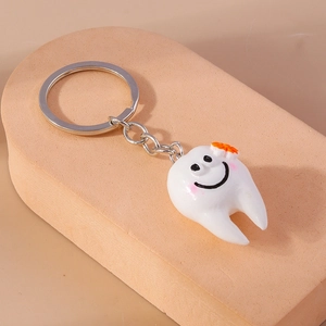 Dettaglio portachiavi a forma di dente bianco con sorriso carino e decorazione floreale