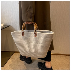 Detail of woven tote bag with natural bamboo handle and beige textured fabric