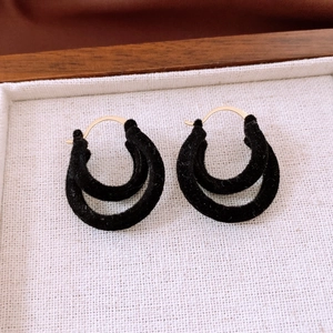 Macro detail of retro double-layer black flocked C-shaped earrings with gold metal hooks