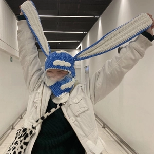 Detail view of long bunny ears on a blue knitted balaclava with cloud patterns