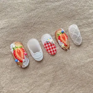 Detail of 3D embossed nail art stickers with strawberry patterns and pearl accents