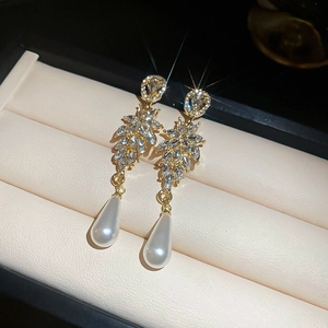 Detail view of leaf-shaped crystal earrings with pearl drops in a jewelry box