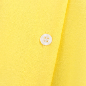 Close-up of a sweet yellow doll collar shirt with a white button and textured fabric