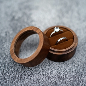 Macro detail of round walnut wood ring box with clear window and velvet interior