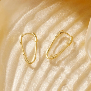 Detailed close-up of polished gold-plated safety pin earrings with zircon stones
