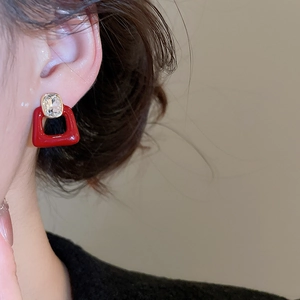 Macro detail of red enamel and zircon stud earring on ear showing fine craftsmanship