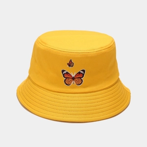 Détail d'un bob en coton jaune avec des motifs de papillons orange brodés dessus