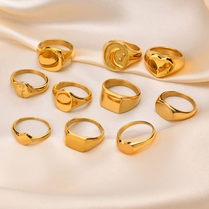Detailed arrangement of diverse gold signet rings on elegant champagne silk fabric