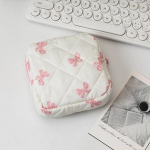 Detailed view of quilted cotton cosmetic bag featuring pink bow patterns and zipper