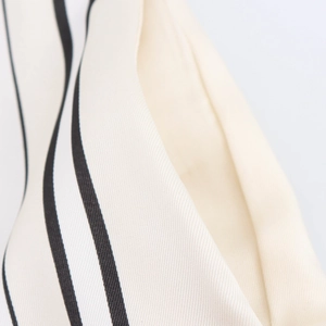 Nahaufnahme der beige-schwarz gestreiften Satin-Weitbeinhose mit Fokus auf Stofftextur