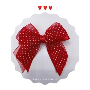 Close-up of red and white polka dot mesh bow hair clip with central knot detail