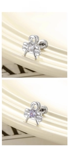 Detail of bow-shaped cartilage stud earrings with heart zircon in clear and light purple