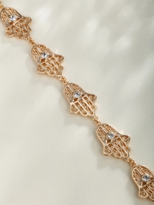 Détail d'un bracelet main de Hamsa doré avec design évidé et strass transparents
