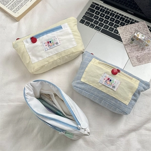 Flat lay of colorful canvas stationery pouches with embroidered labels and zip closure