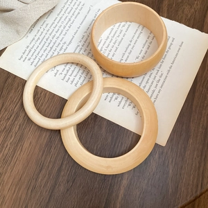 Detailed view of three natural wooden bangles in various widths on a vintage background