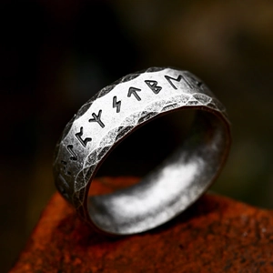 Primer plano de un anillo rúnico vikingo martillado sobre un fondo rústico de piedra roja