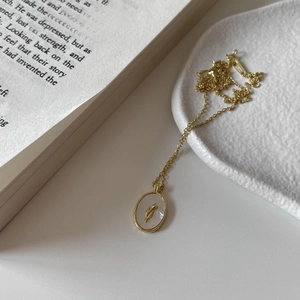 925 silver golden necklace featuring an oval tulip relief pendant on a book background