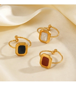 Detail of square vintage rings on silk fabric with engraved gold bands and enamel inlays