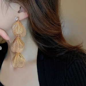 Close-up of gold layered leaf drop earrings with sparkling rhinestones on model