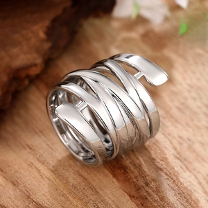 Dettaglio anello a spirale multistrato in argento lucido su superficie in legno