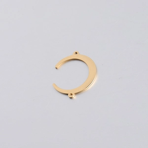 Detail of a golden mirror polished stainless steel crescent moon pendant with two loops