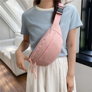 Pink nylon crossbody chest bag with adjustable strap worn by model in a modern room
