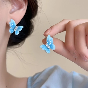 Gros plan de boucles d'oreilles papillon bleues avec émail dégradé et petits diamants