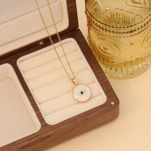 Detail of gold evil eye heart necklace resting in a premium wooden jewelry box