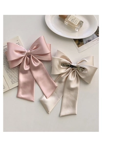Detail of satin bow hair clips in pink and champagne colors with metal spring clips