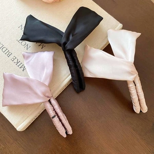Gros plan de barrettes à nœuds en satin noir, lavande et crème sur un bureau