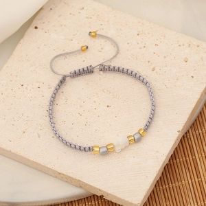 Detailed close-up of handmade gray beaded bracelet with gold and silver accents