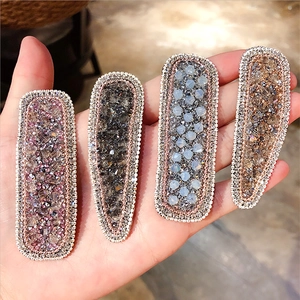 Detailed view of four crystal-encrusted metal hair clips in diverse elegant colors