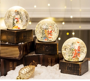 Close-up of vintage wood base Christmas snow globe with Santa and snowman motifs
