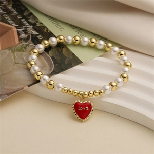 Gold beads and pearl bracelet with a red heart Love pendant on elegant fabric