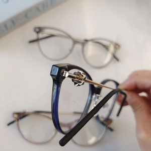 Detail of elegant gold flower-shaped metal hinges on vintage round blue and gold glasses