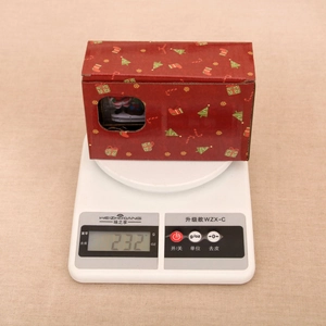 Detailed view of red Christmas train ornament box on a digital scale weighing 232 grams
