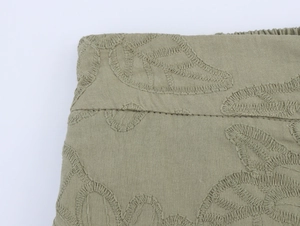 Detailed close-up of leaf embroidery on olive green cotton-linen blazer and trousers